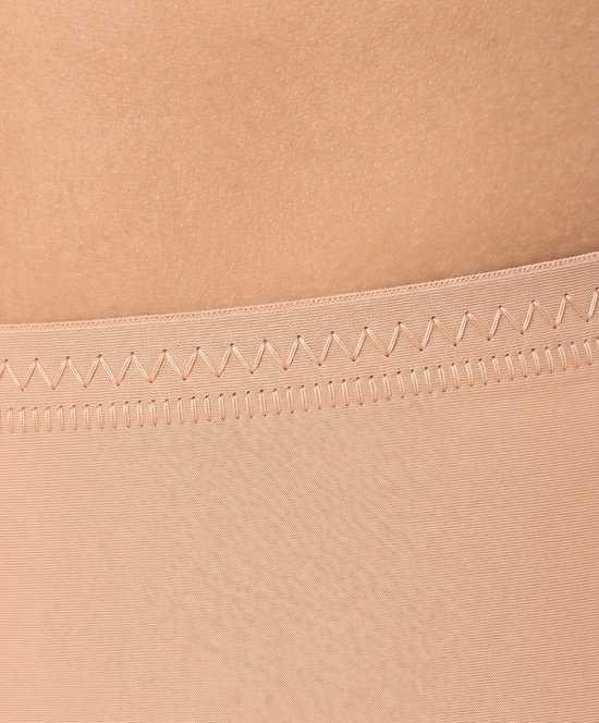 Beige corrigerende shorts met decoratieve zigzag stiksels en platte naden aan de bovenrand.