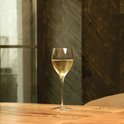 Een glas witte wijn op een houten tafel, met een marmeren achtergrond.