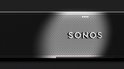 Zwarte Sonos soundbar met geperforeerd rooster en "SONOS" logo, belicht door een spot.