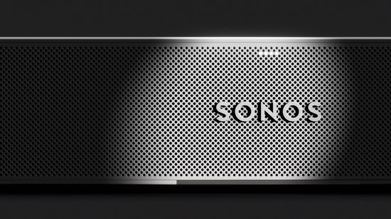 Zwarte Sonos soundbar met geperforeerd rooster en "SONOS" logo, belicht door een spot.