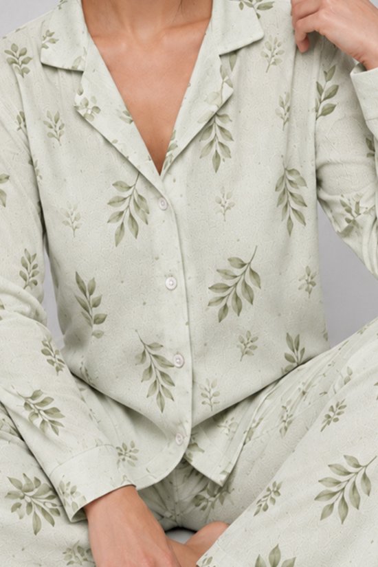 Close-up van een pyjama met knoopsluiting in saliegroen met een bladerenprint.