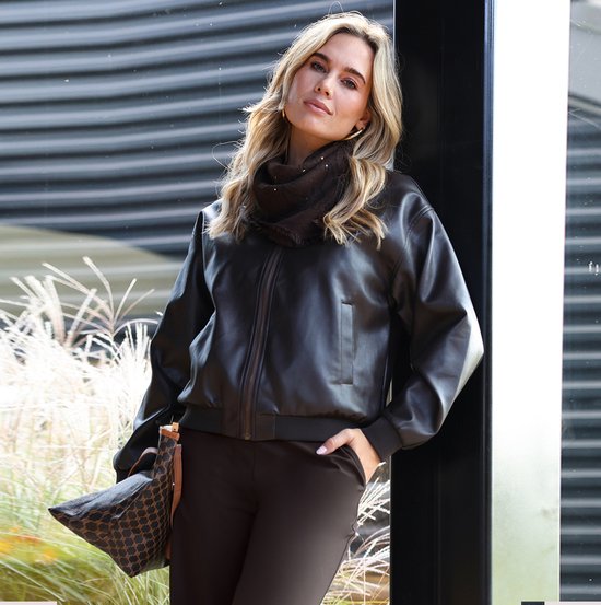Model met donkerbruin faux-leren bomberjack, bijpassende sjaal en tas met patroon.