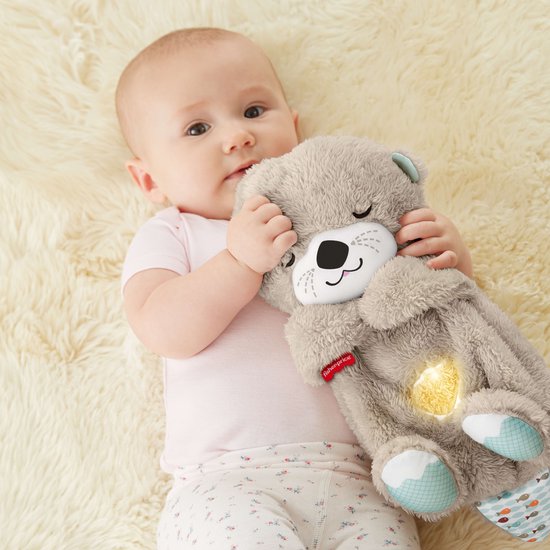Baby houdt een zachte, bruine otter knuffel met gloeiend hartje vast.