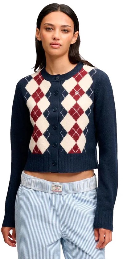 Model in marineblauw vest met ruitpatroon en knoopsluiting, gecombineerd met een gestreepte broek.
