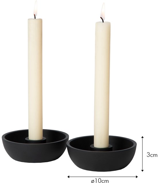Twee brandende dinerkaarsen in zwarte metalen houders met maataanduidingen van 3 cm hoog en 10 cm in diameter.