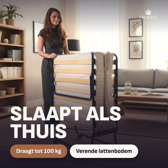 Vrouw in woonkamer naast een verticaal opgevouwen bed met lattenbodem.