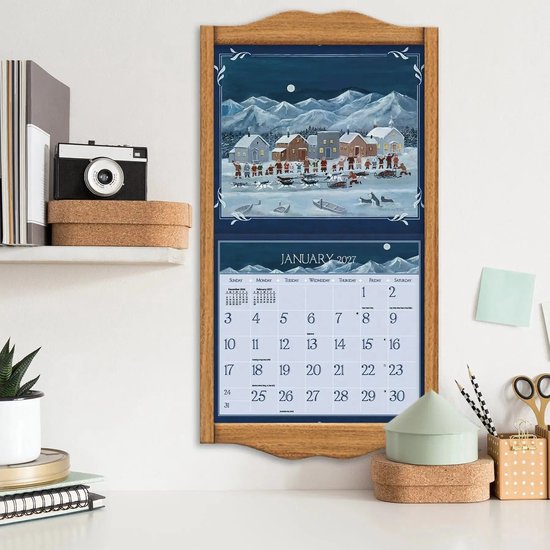 Kalender met winters dorpsschilderij en januari 2027 kalender in houten lijst aan muur.