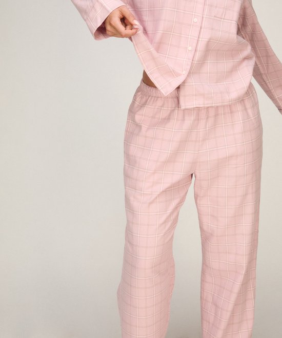 Model in roze geruite pyjamabroek en bijpassend pyjamashirt.