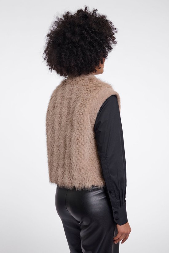 Zijenaanzicht van een model met kort, bruin, pluizig vest over een zwart overhemd.