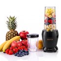 Zwarte Zenvox 1200W blender met mengbeker gevuld met fruit naast een variëteit aan verse vruchten.
