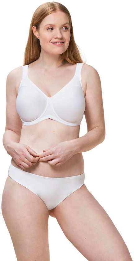 Model met lang rood haar draagt een witte beha en slip, lachend en kijkend naar de zijkant.