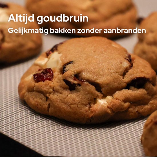 Een gouden, zachte cookie met witte chocolade en cranberry's op een bakmat.