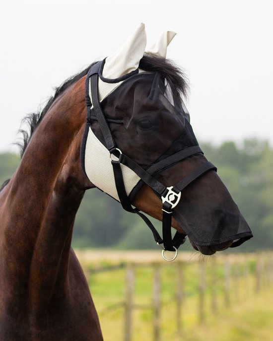 Bruin paard met beige en zwart vliegenmasker met afneembare neusflap en oorbeschermers in een weiland.