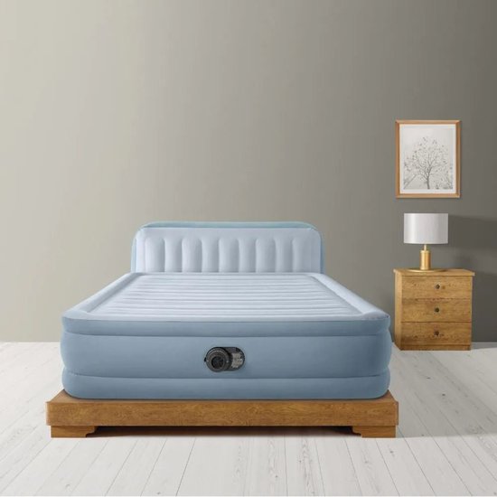 Blauw Intex luchtbed met ingebouwd hoofdbord, geplaatst op een houten frame in een slaapkamer.