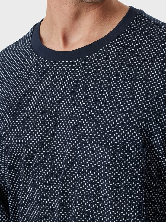 Close-up van de halslijn en stof van de marineblauwe top met een wit geometrisch stippenpatroon.