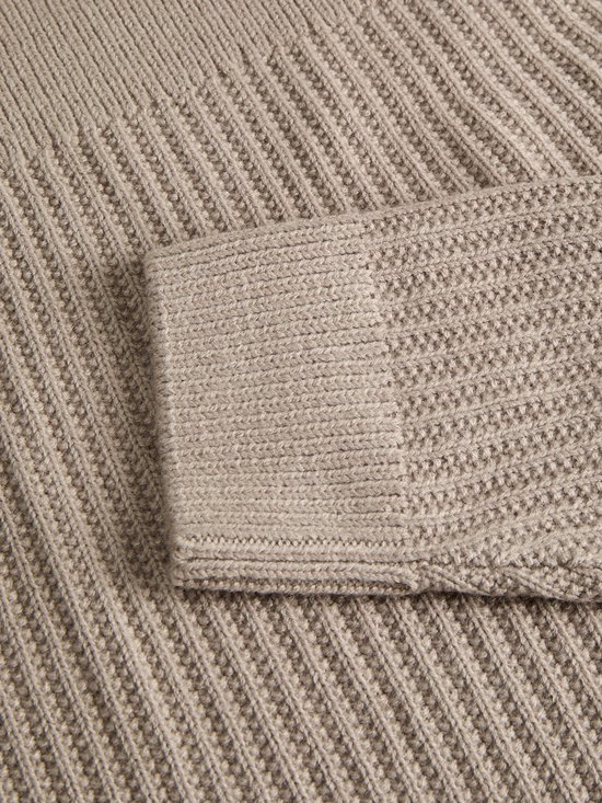 Close-up van de ribgebreide mouwboord van de beige polo.