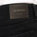 Zwarte jeans met een donkerbruin leren JJ Rebel label op de achterkant.