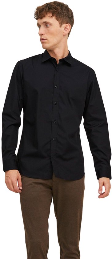 Man in een zwart, lang-mouwig button-down overhemd, staand.