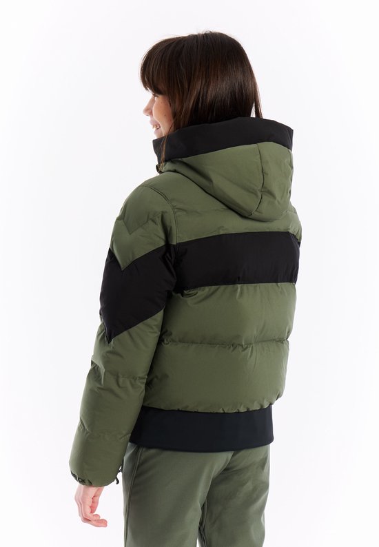 Zijaanzicht van een meisje in groene pufferjas met zwarte banden en groene skibroek.