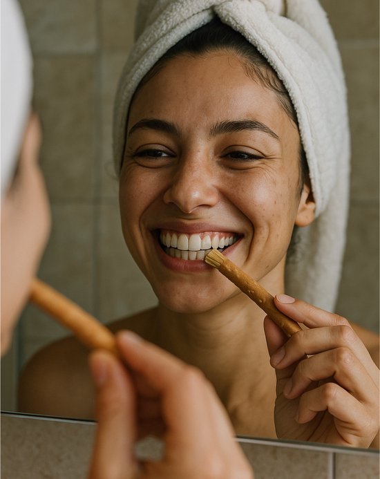 Vrolijke vrouw met handdoek om haar hoofd gebruikt Miswak voor haar tanden.