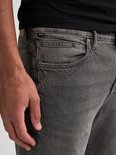 Close-up van een grijze jeans met zakken en een 'Petrol' label.