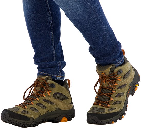 Merrell Moab 3 mid-hoog, olijfgroene suède en mesh wandelschoenen met oranje accenten en blauwe jeans.