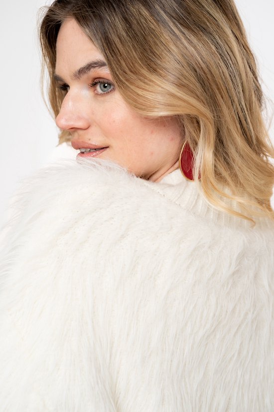 Detailopname van het off-white, harige vest op de schouder van een model met rode oorbellen.