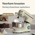 Crème keukenmachine met garde die schuim klopt in de RVS mengkom, naast een chocoladetaart.