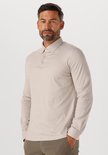 Man met baard draagt een beige longsleeve poloshirt.