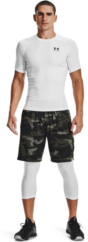 Man met wit, aansluitend sportshirt met korte mouwen, camouflage shorts en witte driekwart leggings.