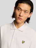 Close-up van lichtroze poloshirt met gele vogel-logo en witte knopen.