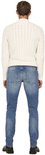 Man met een crème kabeltrui en blauwe jeans, achterkant.