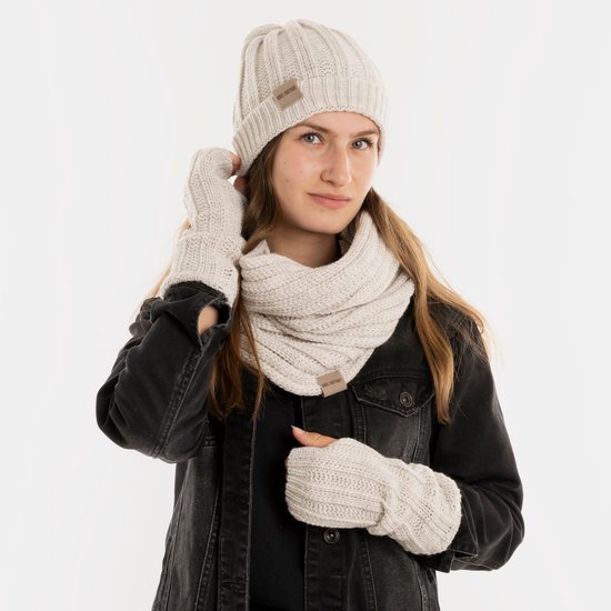 Model met gebreide muts, sjaal en wanten in off-white, met beige labels.