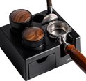 Close-up van zwart tamper station met houten tamper en portafilter.