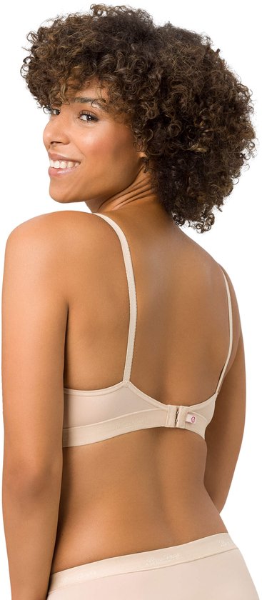 Model draagt een beige beugelvrije BH en slipje, met krullend haar, kijkt over de schouder.