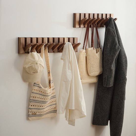 Twee houten kapstokken, de grootste met 10 haken met een grijze jas, 2 beige tassen en een witte blouse.