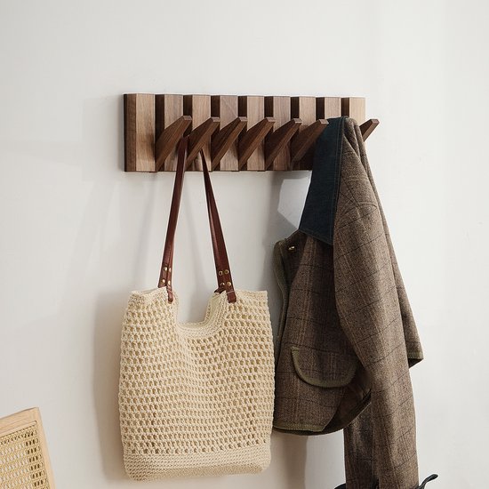 Houten wandkapstok met 8 uitklapbare haken, hieraan hangt een beige tas met bruine hengsels en een bruin geruite jas.