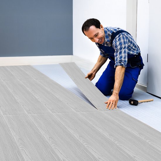 Man legt lichte PVC-vloerplanken met houtnerfpatroon.