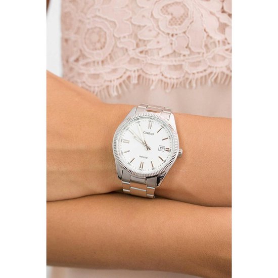 Montre Casio argentée à cadran blanc portée au poignet d'une femme.