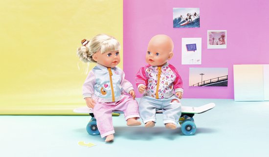 Twee BABY born poppen op een skateboard. Eén draagt een lichtblauw jasje met roze mouwen en een roze broek. De ander draagt een roze jasje en een lichtblauwe broek.