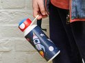 Enfant tenant une gourde blanche avec un imprimé spatial : fusée, astronaute, planètes.