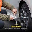 Een persoon gebruikt een zilverkleurige kruissleutel om een wielbout los te draaien.