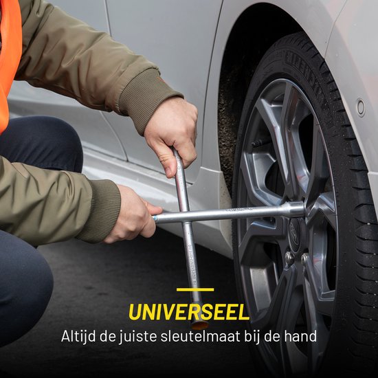 Een persoon gebruikt een zilverkleurige kruissleutel om een wielbout los te draaien.