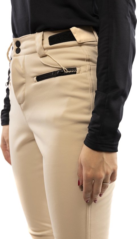 Detail van een beige skibroek met zwarte ritssluiting op de zak en zwarte mouwen.