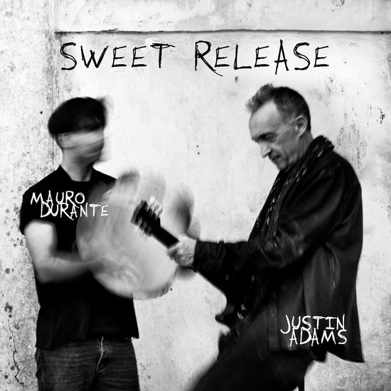 Albumhoes met "SWEET RELEASE" bovenaan. Twee mannen, Justin Adams en Mauro Durante, met gitaren.