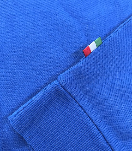 Detail van blauwe sweater: Italiaanse vlag aan de zijkant, geribbelde mouw.