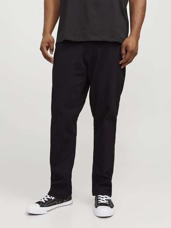 Man in een zwarte T-shirt en zwarte jeans met sneakers.