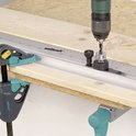 Wolfcraft deuvelmal met boor op een houten plank, met klemmen bevestigd.