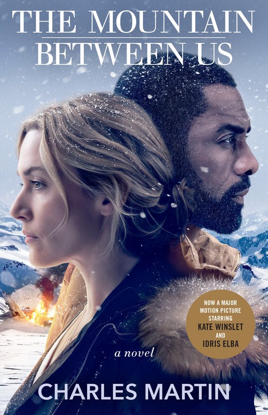 Boekomslag van 'The Mountain Between Us' met Kate Winslet en Idris Elba in de sneeuw. Tekst: 'THE MOUNTAIN BETWEEN US', 'a novel', 'CHARLES MARTIN'.