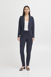 Model in donkerblauwe blazer met bijpassende broek en witte top.